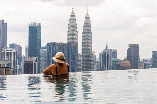 Woman relaxing in infinity pool with Petronas Towers view