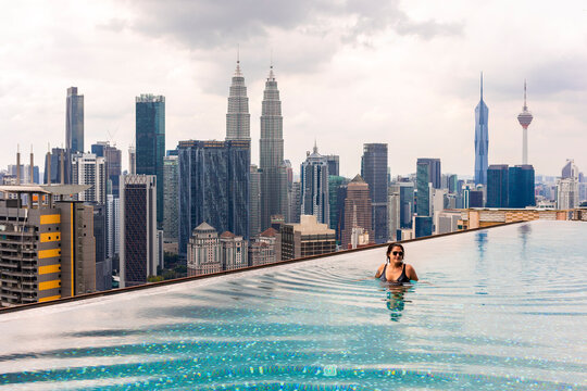 Woman relaxing in infinity pool with Petronas Towers view
