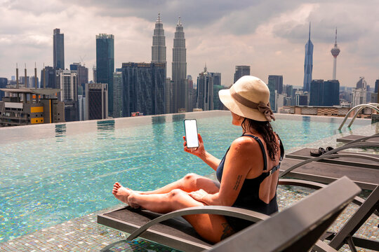 Woman relaxing by rooftop pool with Petronas Towers view