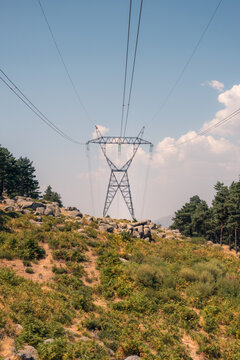 High-voltage power lines over rocky hillside landscape