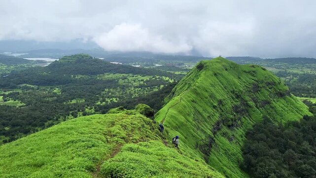 A Sahyadri trekker stands before a breathtaking lush green mountain range, surrounded by drifting clouds and wild beauty. A stunning 4K glimpse of adventure, freedom, and monsoon magic.