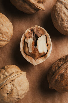 Close-up of cracked walnut halves on rustic brown backdrop