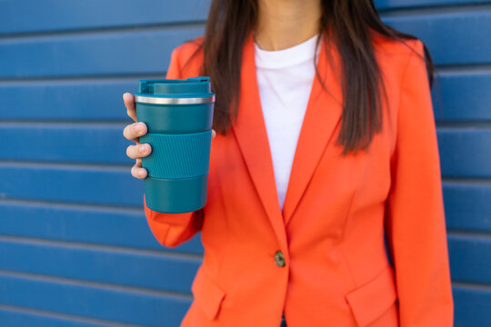 Businesswoman holding coffee in orange blazer