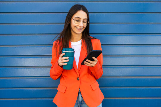 Business woman in orange jacket with smartphone