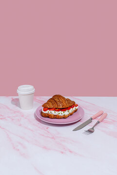 Croissant with strawberry and cream on pink marble