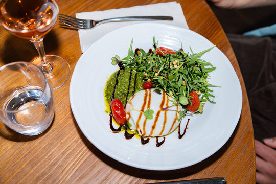Mediterranean burrata salad with arugula and pesto drizzle