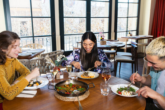 Friends sharing Mediterranean paella at a cozy restaurant