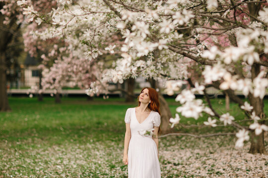 Woman in white dress under blooming magnolia tree