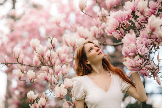 Woman enjoying magnolia blossoms in soft spring light