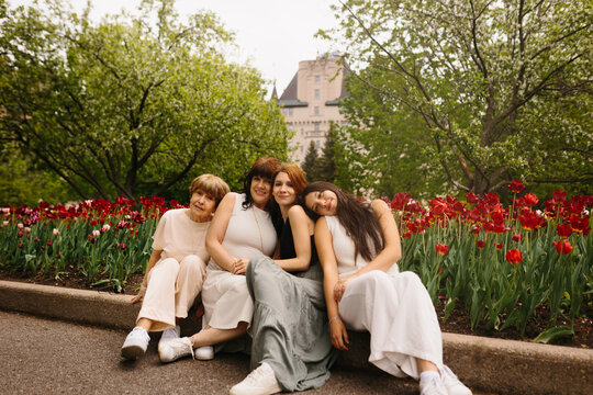 Four women relaxing by tulips in a city park in spring