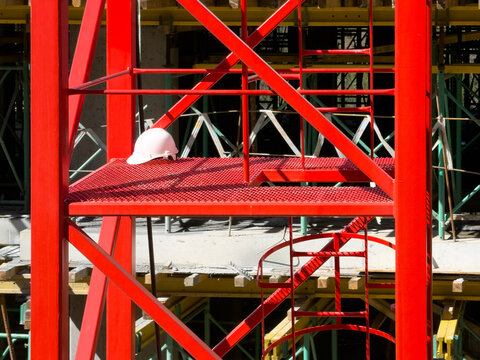 Red steel construction scaffold platform with safety helmet