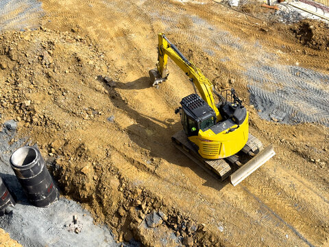 Excavator digging foundation trench at active construction site