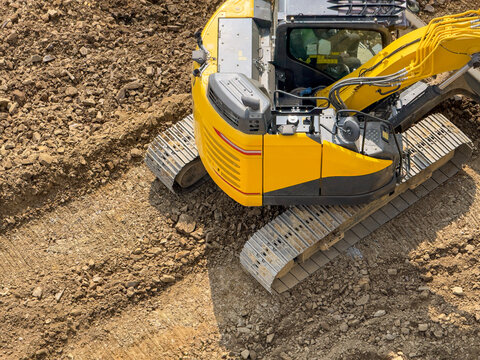 Yellow excavator on dirt at construction site, top view