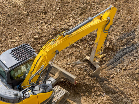Excavator arm digging soil at construction site, top view