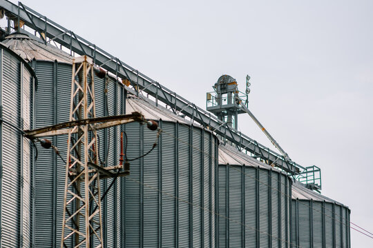 View of towering metal silos and a weathered utility pole reach towards the muted sky, creating a stark industrial landscape, Sremska Mitrovica, Vojvodina, Serbia.
