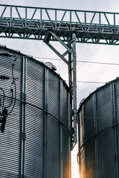 View of industrial silos gleaming under the sun, their corrugated metal reflecting light, connected by overhead structures, Sremska Mitrovica, Vojvodina, Serbia.
