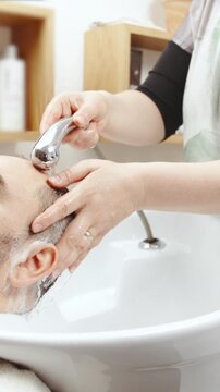Washing male person short hair at hairdresser salon
