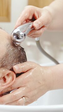 Washing male person short hair at hairdresser salon