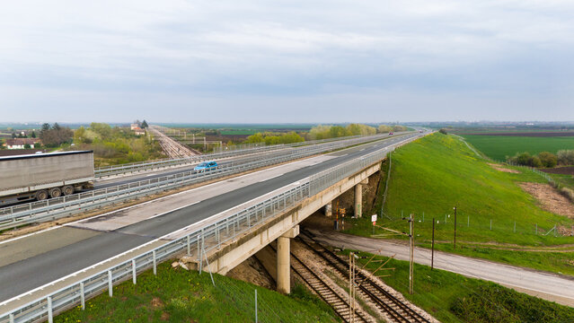 Aerial view of the highway stretching towards the horizon amidst the green fields and cloudy sky, Sremska Mitrovica, Vojvodina, Serbia.