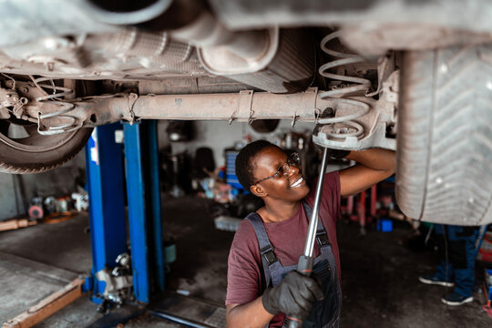 Mechanic works on car in auto shop during daylight hours