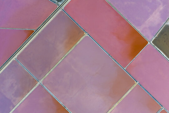 Aerial view of the pink and red hues of the salt flats create a stunning geometric mosaic from above, San Pedro del Pinatar, Region of Murcia, Spain.