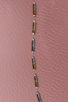 Aerial view of boats sailing on the pink waters of Las Salinas, a striking contrast of colors and textures under the sun, San Pedro del Pinatar, Region of Murcia, Spain.