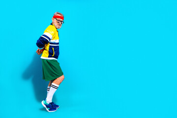 Obraz premium Elderly man in retro sportswear posing confidently for senior fitness and active lifestyle portrait on bright blue background