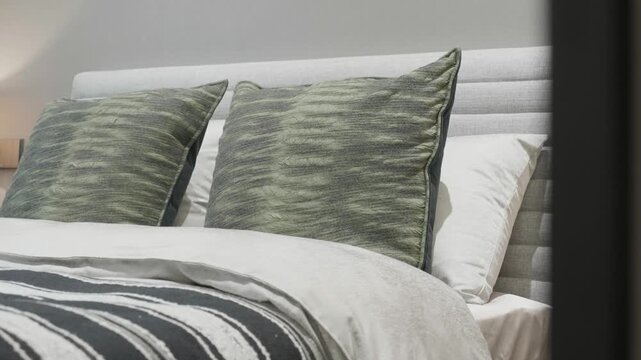 Modern minimalist bedroom bed headboard with upholstered backrest and green patterned cushions in close-up