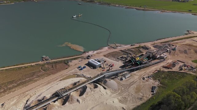 Aerial view of active sand quarry and aggregate processing plant beside a lake