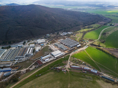 Aerial view of the industrial complex nestled between the verdant fields and the dark, wooded mountains, Detva, Banskobystricky kraj, Slovakia.