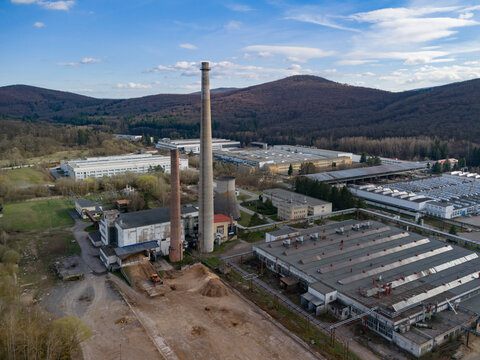 Aerial view of industrial buildings with tall chimneys piercing the skyline, a landscape where urban meets nature's green embrace, Detva, Banskobystricky kraj, Slovakia.