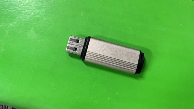 Silver Metallic USB Flash Drive Lying Horizontally on Solid Bright Green Background Studio Shot
Keywords: