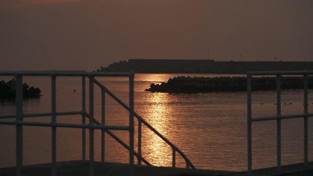 防波堤の階段から見る波けしブロックのある夕日の海