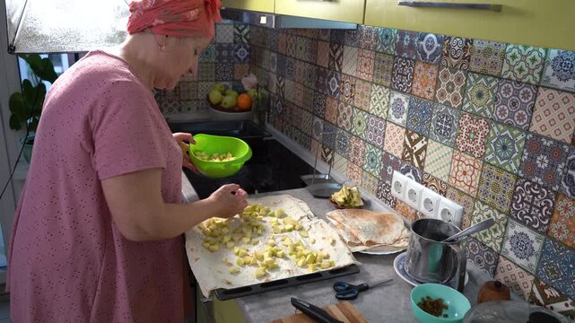 Woman cooking food at home. Wrap apples in pita bread. Make a fruit roll.