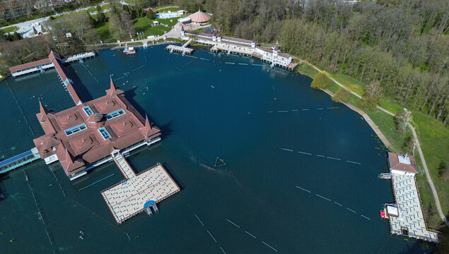 Aerial view of the Heviz Lake, where the dark blue waters meet the warm hues of the bathhouse roofs and the surrounding lush greenery, Heviz, Zala, Hungary.