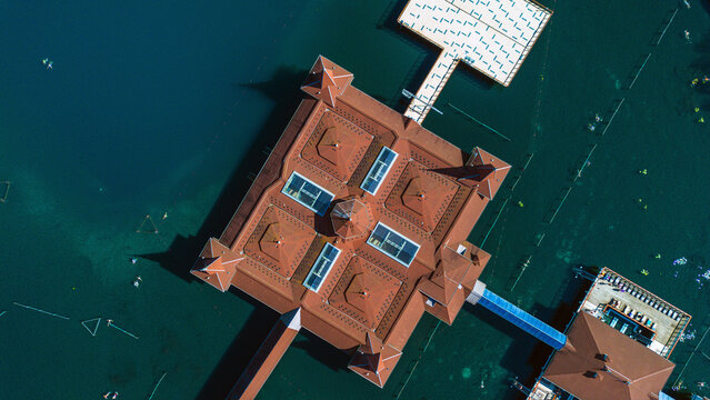 Aerial view of a building with a red roof and a bridge on the water, where people swim, Heviz, Zala, Hungary.