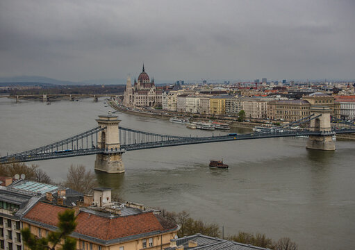 View of the Szechenyi Chain Bridge elegantly spans the flowing Danube, with the Hungarian Parliament Building standing majestically, Budapest, Hungary.
