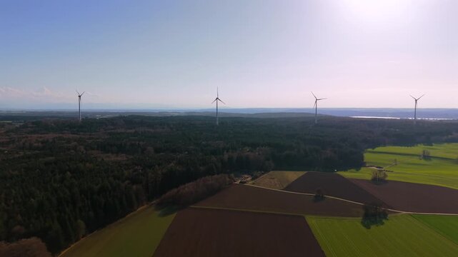 Wind farm with multiple wind generators and wind power turbines near Starnberg, Germany. Scenic rural landscape with forest edge and agricultural land, green energy production.