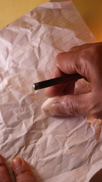 Close up of hand erasing pencil marks on white paper with white eraser