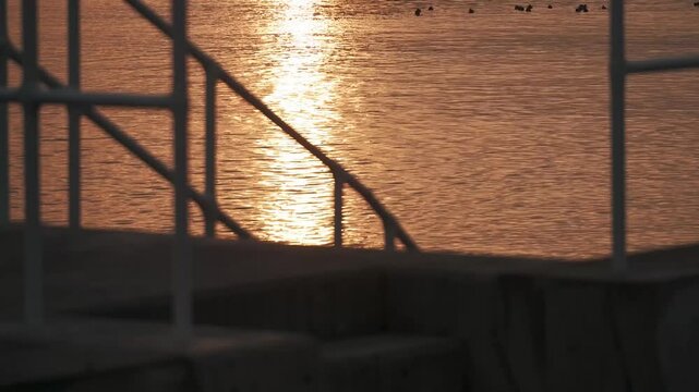 防波堤の階段から見る波けしブロックのある夕日の海