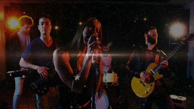 Vocalist stepping forward and singing, band performing music while stars and flares raising climax