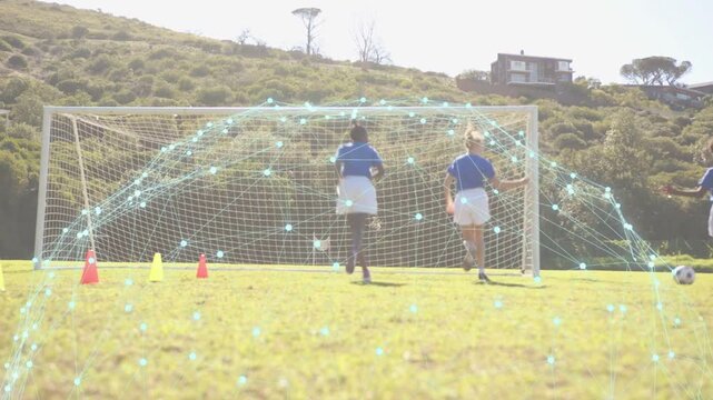 Two soccer players defending goal while kicker kicking ball, hologram overlaying goal in drill