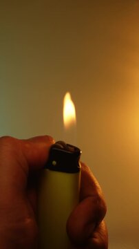 A man's hand turns on a piezoelectric gas lighter in the dark and a bright blue yellow flame appears. Fire magic