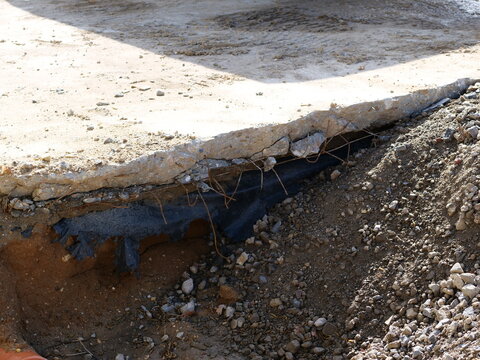  cross-section of a concrete slab during an excavation
project. The image shows the structural layers, including a broken concrete
edge, rusted wire reinforcement, and a black damp-proof membrane 