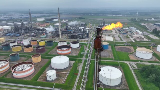 Industrial interior. Panorama of an oil warehouse with many tanks and cisterns in a refinery. Chimney with a burning torch and gas pollution in front. Production of fuels from petroleum. Oil refinery.
