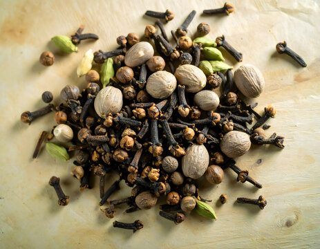 Dried cloves nutmeg and cardamom spices on wooden background