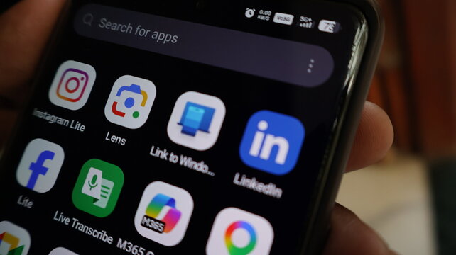 A person holding a smartphone with various social media apps on the screen