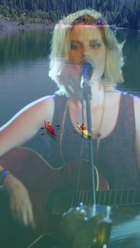 Vertical video: Overlay appearing singer performing singing playing guitar over lake for crowd