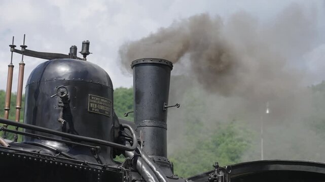 Detial of Historic steam locomotive standing on tracks with thick steam and smoke. Vintage steam engine at the station, Central Europe, 4K, ProRes, 50fps.