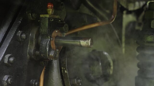 Close up of mechanical steaming details, wheels and piston of a vintage steam engine. Historic locomotive, industrial heritage, 4K, ProRes, 50fps.
